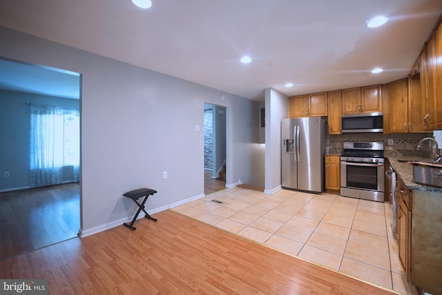 12805 Poplar St, Silver Spring, MD 20904 - kitchen featuring stainless steel appliances, light wood finished floors, brown cabinetry, recessed lighting, and dark stone counters