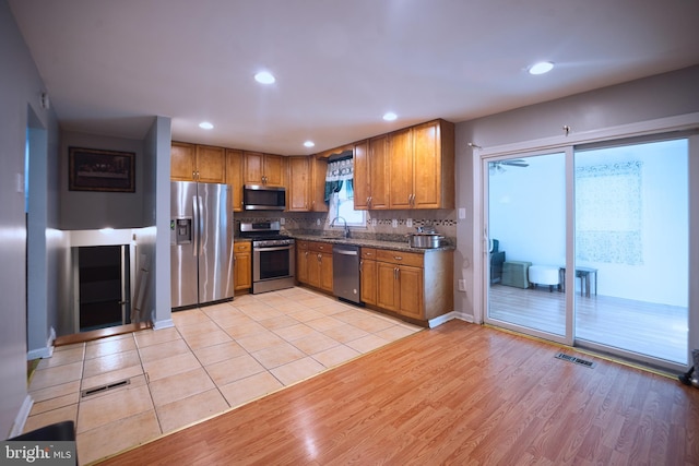 12805 Poplar St, Silver Spring, MD 20904 - kitchen with appliances with stainless steel finishes, brown cabinets, light wood-style floors, recessed lighting, and dark stone counters