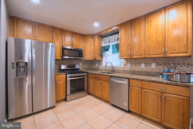 12805 Poplar St, Silver Spring, MD 20904 - kitchen with appliances with stainless steel finishes, brown cabinetry, light tile patterned floors, dark stone counters, and tasteful backsplash