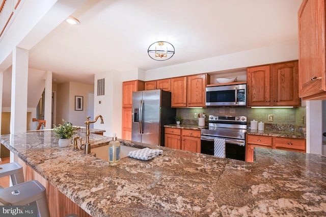 4119 Waterview Dr, Edgewater, MD 21037 - kitchen with stainless steel appliances, backsplash, brown cabinetry, stone countertops, and a breakfast bar area