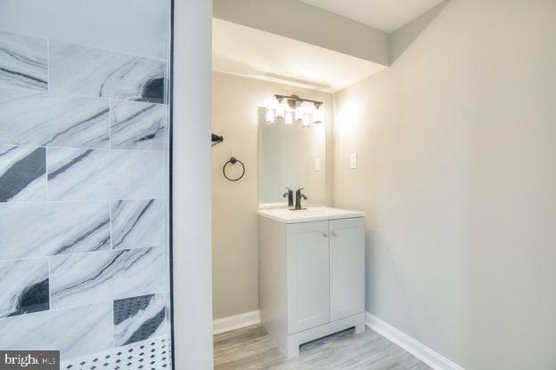 429 N Lakewood Ave, Baltimore, MD 21224 - bathroom with vanity, tiled shower, and wood finished floors