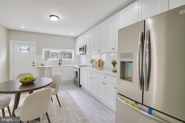 429 N Lakewood Ave, Baltimore, MD 21224 - kitchen featuring stainless steel appliances, plenty of natural light, light wood-style flooring, backsplash, and recessed lighting