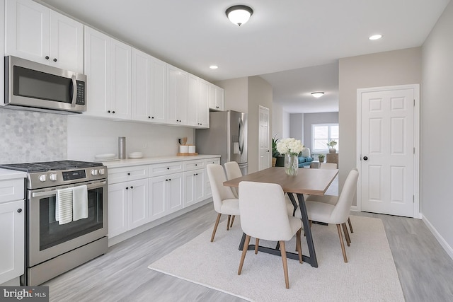 429 N Lakewood Ave, Baltimore, MD 21224 - kitchen with stainless steel appliances, light wood-style floors, backsplash, white cabinets, and recessed lighting