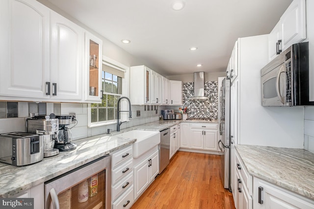 9016 Greylock St, Alexandria, VA 22308 - kitchen with stainless steel appliances, wall chimney exhaust hood, decorative backsplash, light wood finished floors, and recessed lighting
