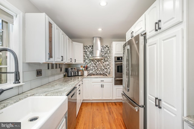 9016 Greylock St, Alexandria, VA 22308 - kitchen featuring appliances with stainless steel finishes, wall chimney range hood, a warming drawer, backsplash, and white cabinets