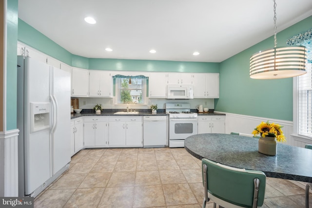 510 Revere Ct, Hockessin, DE 19707 - kitchen featuring white appliances, dark countertops, wainscoting, white cabinets, and pendant lighting