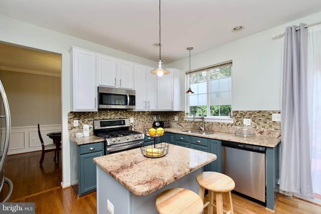 14813 Blackburn Rd, Burtonsville, MD 20866 - kitchen with appliances with stainless steel finishes, a kitchen island, light stone countertops, white cabinetry, and a breakfast bar area
