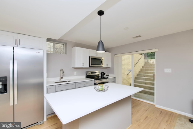 14813 Blackburn Rd, Burtonsville, MD 20866 - kitchen featuring appliances with stainless steel finishes, light countertops, light wood-type flooring, white cabinets, and hanging light fixtures