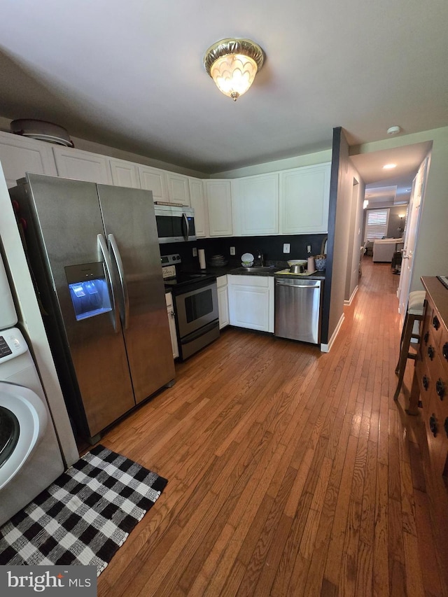 214 Dennison St, Colonial Beach, VA 22443 - kitchen featuring appliances with stainless steel finishes, hardwood / wood-style flooring, white cabinets, and dark countertops