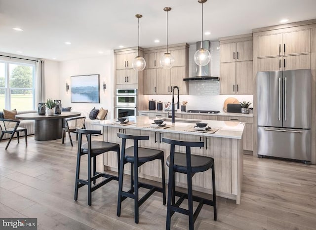 LOT29-109 Tiffany Ln, Spring City, PA 19475 - kitchen featuring stainless steel appliances, wall chimney exhaust hood, a breakfast bar area, light wood-style floors, and recessed lighting
