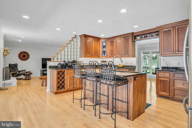 220 Longview Blvd, Gettysburg, PA 17325 - kitchen featuring ornamental molding, a breakfast bar area, brown cabinets, light wood-type flooring, and glass insert cabinets