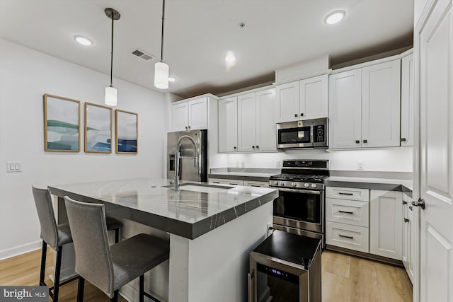 6107 Fairview Farm Dr Unit 306, Alexandria, VA 22315 - kitchen with stainless steel appliances, light wood finished floors, a kitchen bar, hanging light fixtures, and dark countertops