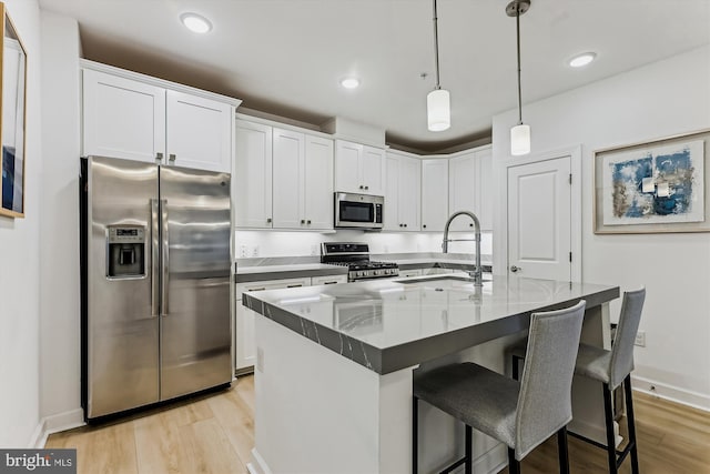 6107 Fairview Farm Dr Unit 306, Alexandria, VA 22315 - kitchen with appliances with stainless steel finishes, light wood-type flooring, a kitchen bar, white cabinetry, and pendant lighting