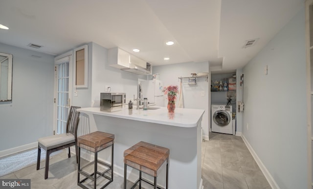 1842 N Capitol St NW, Washington, DC 20002 - kitchen with washer / clothes dryer, a breakfast bar area, recessed lighting, a peninsula, and light countertops