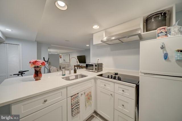 1842 N Capitol St NW, Washington, DC 20002 - kitchen featuring freestanding refrigerator, a peninsula, stainless steel microwave, black electric stovetop, and light countertops