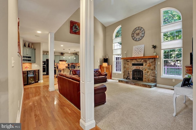 404 Herington Dr, Reading, PA 19608 - living room featuring decorative columns, a towering ceiling, a fireplace, and light wood-type flooring