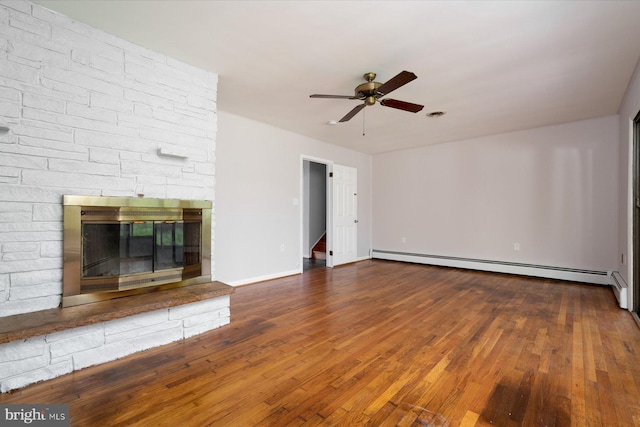 3990 View Top Rd, Ellicott City, MD 21042 - unfurnished living room featuring a baseboard heating unit, ceiling fan, wood finished floors, and a stone fireplace