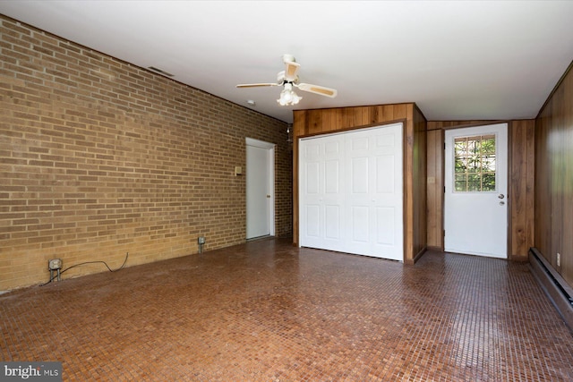 3990 View Top Rd, Ellicott City, MD 21042 - unfurnished bedroom with brick wall, baseboard heating, a closet, wood walls, and a ceiling fan