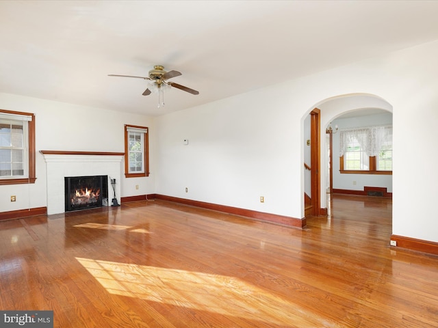 55 W Duck St, Front Royal, VA 22630 - unfurnished living room with wood finished floors, ceiling fan, arched walkways, and a lit fireplace