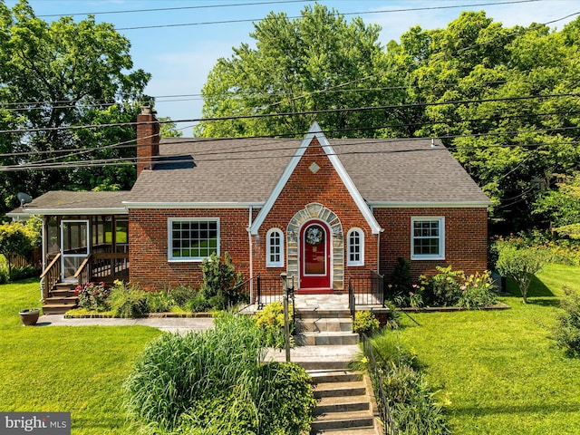 55 W Duck St, Front Royal, VA 22630 - tudor-style house with brick siding, a chimney, a sunroom, a front lawn, and roof with shingles