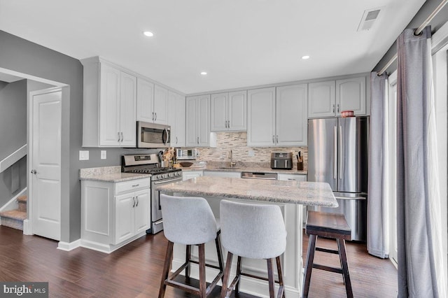 506 Masters Dr, Blackwood, NJ 08012 - kitchen with stainless steel appliances, dark wood finished floors, a breakfast bar area, light stone countertops, and recessed lighting