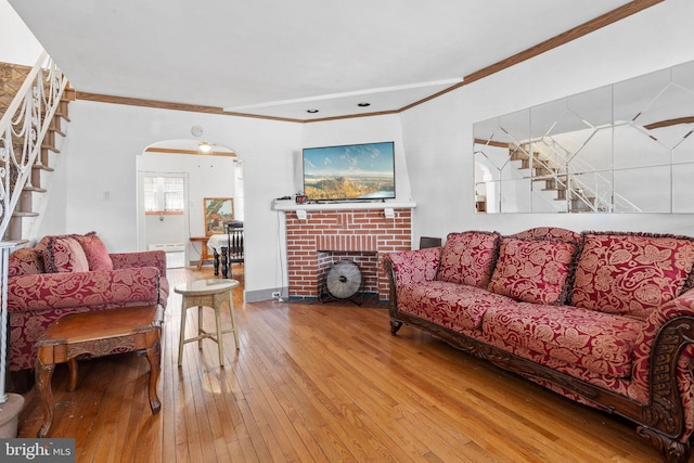 5563 Loretto Ave, Philadelphia, PA 19124 - living room featuring arched walkways, stairs, wood-type flooring, crown molding, and a fireplace