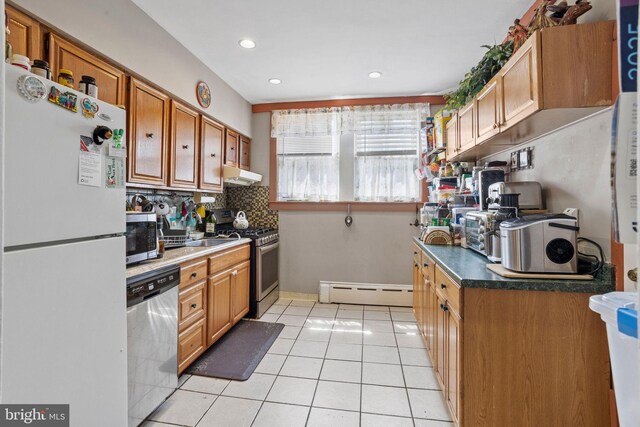 5563 Loretto Ave, Philadelphia, PA 19124 - kitchen with stainless steel appliances, under cabinet range hood, baseboard heating, light tile patterned flooring, and tasteful backsplash