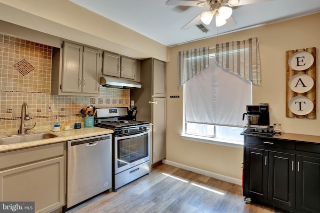 28 Wister Way, Reading, PA 19606 - kitchen with stainless steel appliances, under cabinet range hood, a ceiling fan, light wood-style flooring, and backsplash