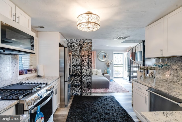 7723 Meath Rd, Baltimore, MD 21222 - kitchen featuring appliances with stainless steel finishes, light wood finished floors, open floor plan, and backsplash