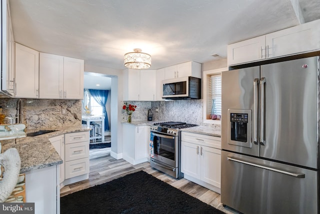 7723 Meath Rd, Baltimore, MD 21222 - kitchen with stainless steel appliances, light wood-style floors, white cabinets, and tasteful backsplash