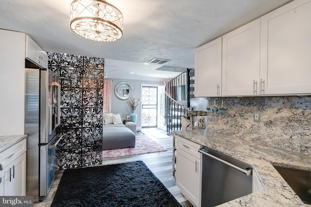 7723 Meath Rd, Baltimore, MD 21222 - kitchen with appliances with stainless steel finishes, open floor plan, light wood-type flooring, white cabinetry, and light stone counters