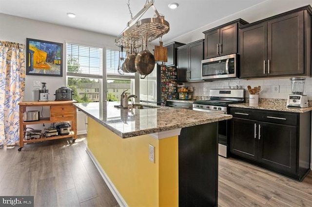 2041 Ruby Turn, Bowie, MD 20721 - kitchen featuring appliances with stainless steel finishes, light wood-type flooring, light stone countertops, an island with sink, and decorative backsplash