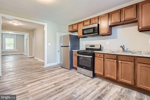 2710 The Alameda, Baltimore, MD 21218 - kitchen featuring stainless steel appliances, light wood-style floors, and brown cabinetry