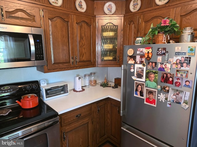 1220 Manatawny St, Pottstown, PA 19464 - kitchen with stainless steel appliances, light countertops, brown cabinetry, and glass insert cabinets