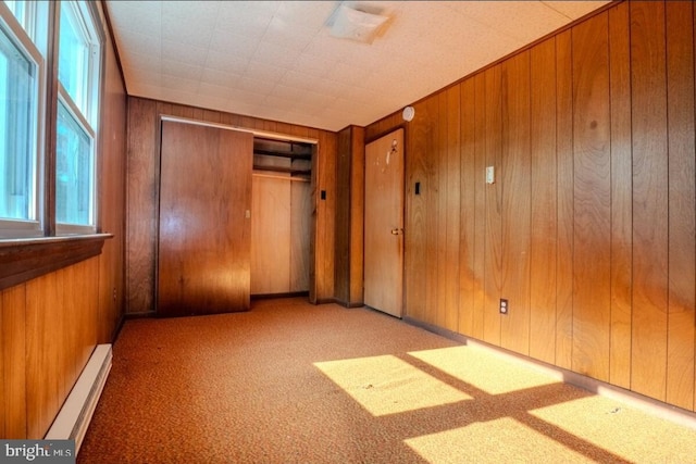 102 Spring St, Bridgeton, NJ 08302 - unfurnished bedroom featuring baseboard heating, wood walls, carpet floors, and a closet