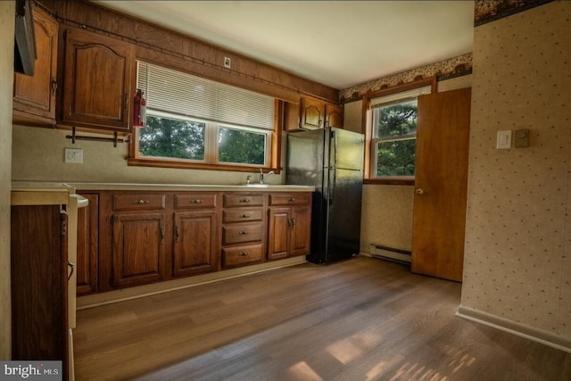 102 Spring St, Bridgeton, NJ 08302 - kitchen with freestanding refrigerator, wood finished floors, a baseboard radiator, wallpapered walls, and brown cabinetry