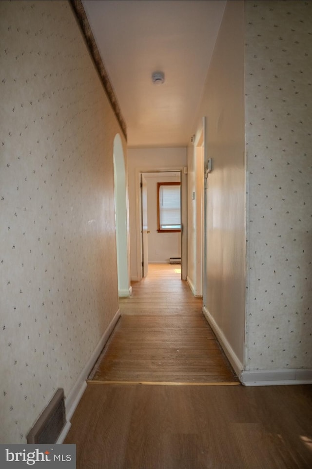 102 Spring St, Bridgeton, NJ 08302 - corridor with wallpapered walls, wood finished floors, arched walkways, and a baseboard radiator