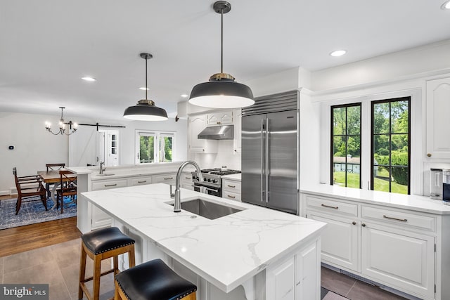 1263 Argyle Rd, Berwyn, PA 19312 - kitchen featuring high quality appliances, under cabinet range hood, a peninsula, white cabinetry, and a center island with sink