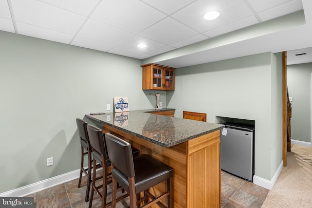 1263 Argyle Rd, Berwyn, PA 19312 - kitchen with refrigerator, brown cabinets, a drop ceiling, a breakfast bar, and glass insert cabinets