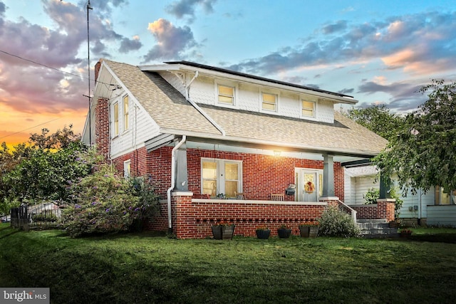 545 W King St, Littlestown, PA 17340 - back of property at dusk with brick siding, roof with shingles, and a yard
