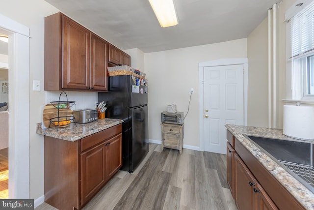 124 E Ormond Ave, Haddon Township, NJ 08107 - kitchen with freestanding refrigerator, light wood-style flooring, light stone counters, and brown cabinets
