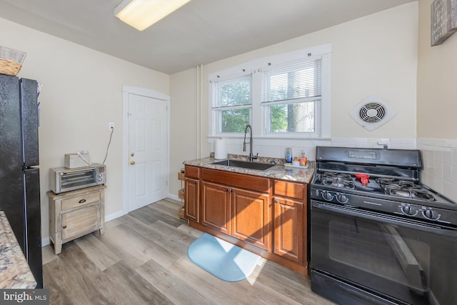 124 E Ormond Ave, Haddon Township, NJ 08107 - kitchen featuring black appliances, brown cabinetry, light wood finished floors, and light stone countertops