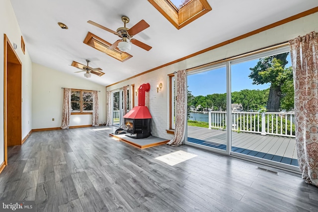 8283 Choptank Rd, Pasadena, MD 21122 - unfurnished living room featuring a skylight, a wood stove, plenty of natural light, ceiling fan, and vaulted ceiling