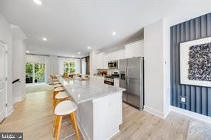 1250 Barkleyridge Ln, Glen Burnie, MD 21060 - kitchen with appliances with stainless steel finishes, white cabinets, light wood-style floors, a center island, and a breakfast bar area