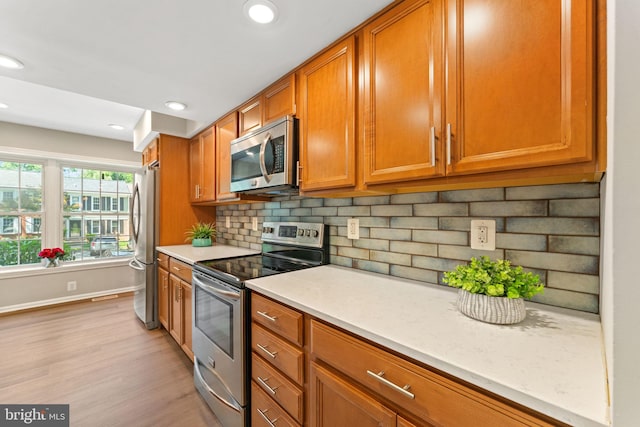 8573 Chester Grove Ct, Springfield, VA 22153 - kitchen featuring stainless steel appliances, light countertops, brown cabinets, light wood-type flooring, and backsplash