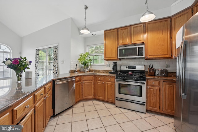 13297 Osage Dr, Woodbridge, VA 22193 - kitchen featuring stainless steel appliances, decorative backsplash, lofted ceiling, and brown cabinets