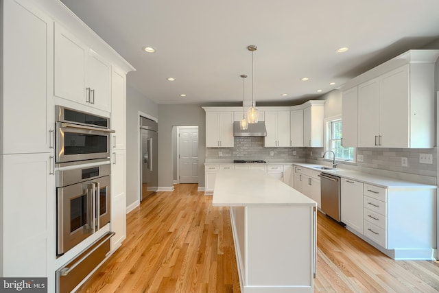 10905 Powers Ave, Cockeysville, MD 21030 - kitchen with under cabinet range hood, stainless steel appliances, a warming drawer, decorative backsplash, and white cabinetry