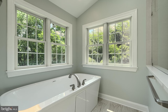 10905 Powers Ave, Cockeysville, MD 21030 - bathroom featuring a freestanding bath, healthy amount of natural light, marble look tiles, and vaulted ceiling
