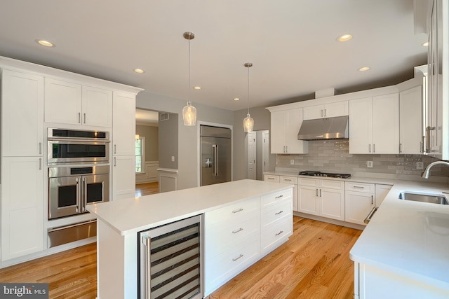 10905 Powers Ave, Cockeysville, MD 21030 - kitchen with beverage cooler, stainless steel appliances, under cabinet range hood, a warming drawer, and light wood-style flooring