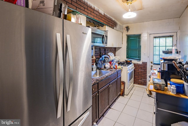 41161/2 Belle Ave, Baltimore, MD 21215 - kitchen with appliances with stainless steel finishes, light tile patterned floors, dark brown cabinetry, and brick wall